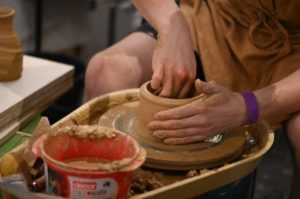 Photo of Sam throwing a ceramic vessel on a pottery wheel